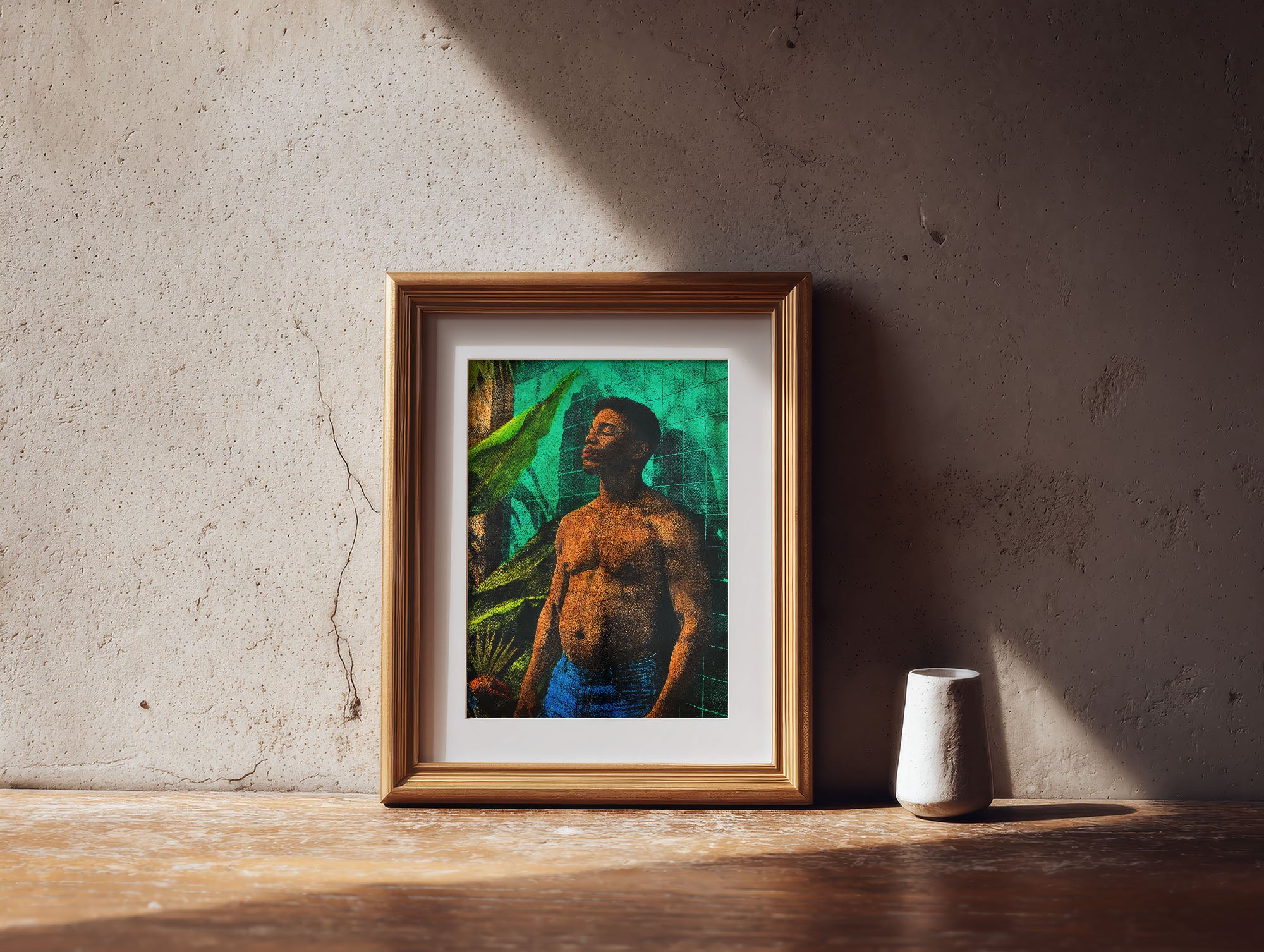 Framed artwork of a shirtless man standing by green tiles, placed on a wooden table with soft sunlight on the wall.