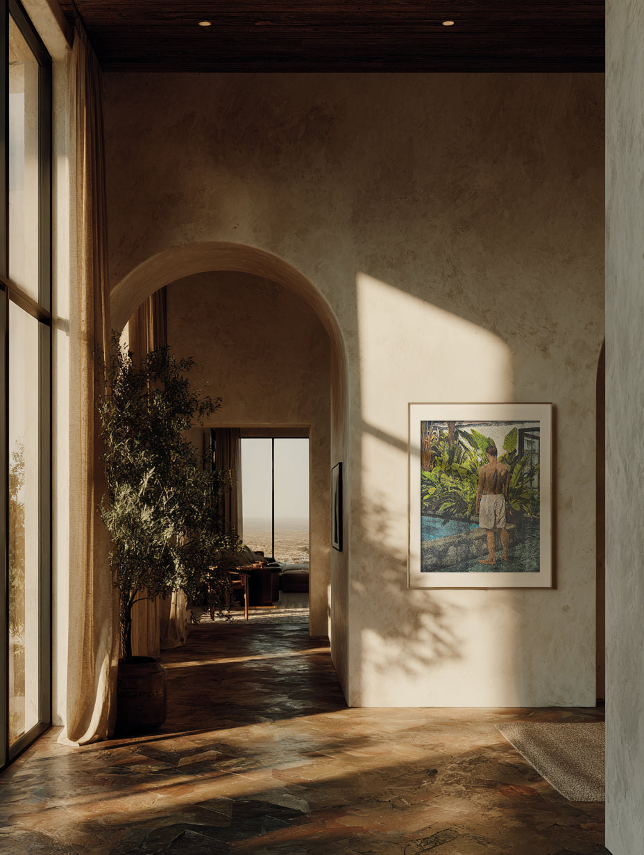 Framed monotype print hanging in a sunlit interior with an archway and large indoor plants.